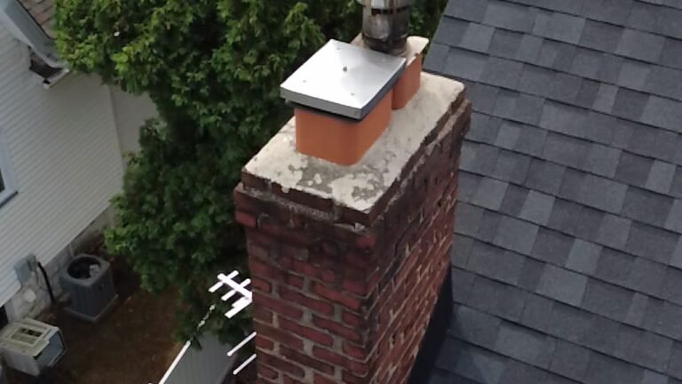 Brick chimney with a white crown and metal cap on a shingled roof, Montclair, NJ