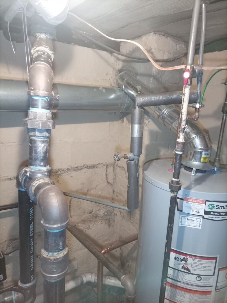 Pipes and water heater in a basement utility area near the chimney connection, Jersey City, NJ