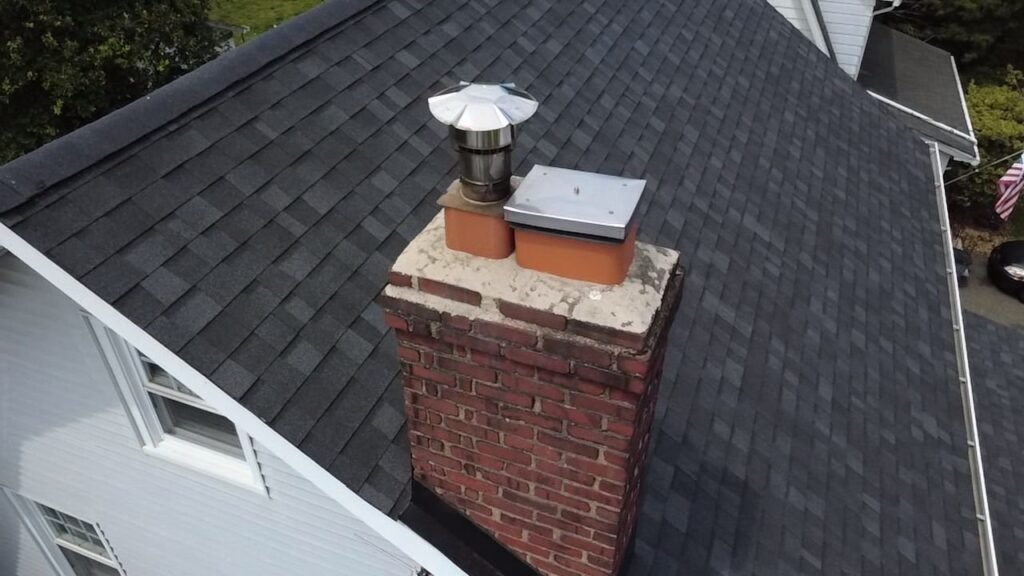Chimney top with a crown and metal cap seen from the roof edge, Montclair, NJ