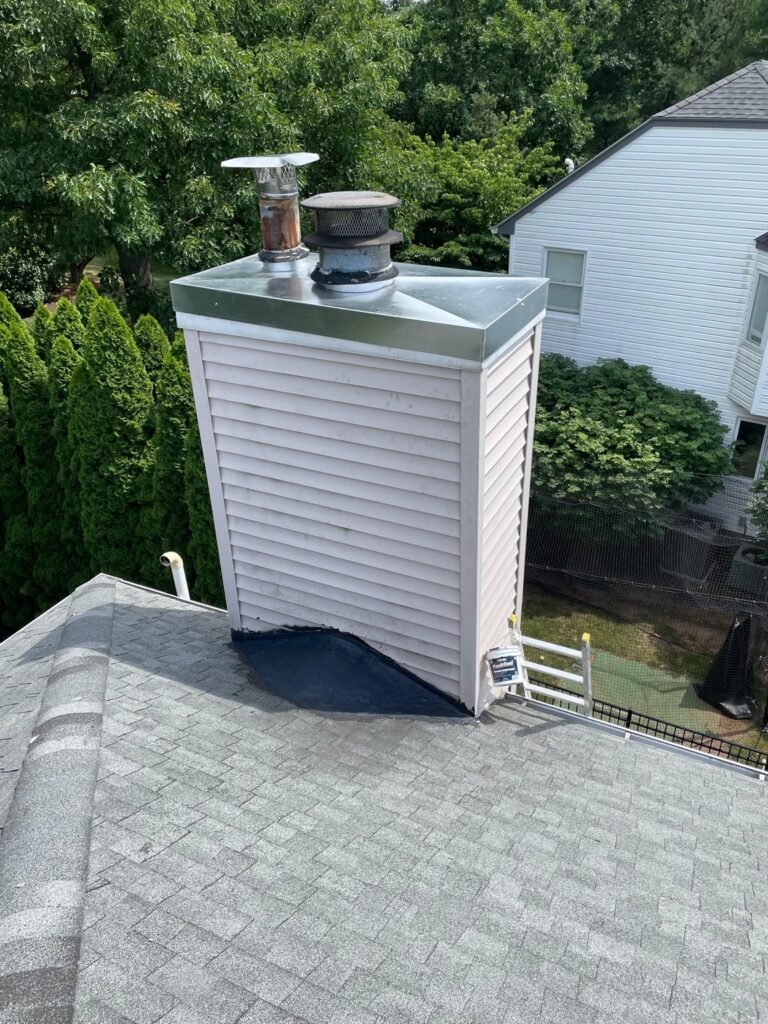 Vinyl-sided chimney chase with flashing at its base, seen from above the roof
