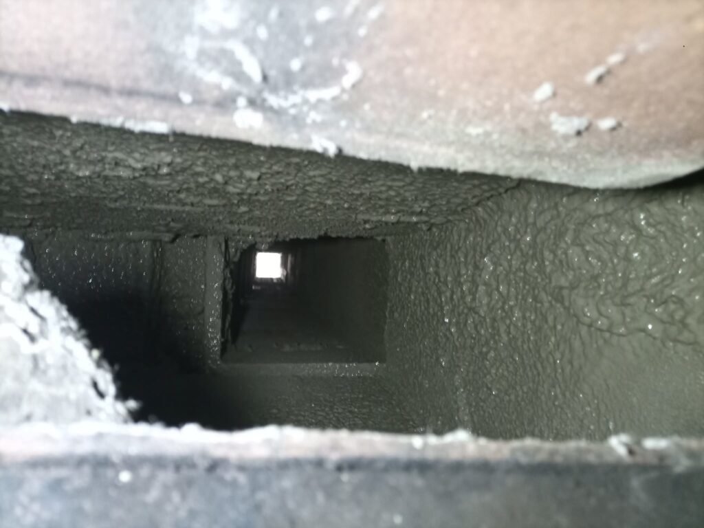 Sooty, rusted metal damper area at the bottom of the smoke chamber