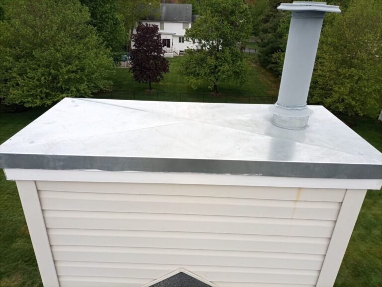 New metal chase cover with a flue pipe on a vinyl-sided chimney chase