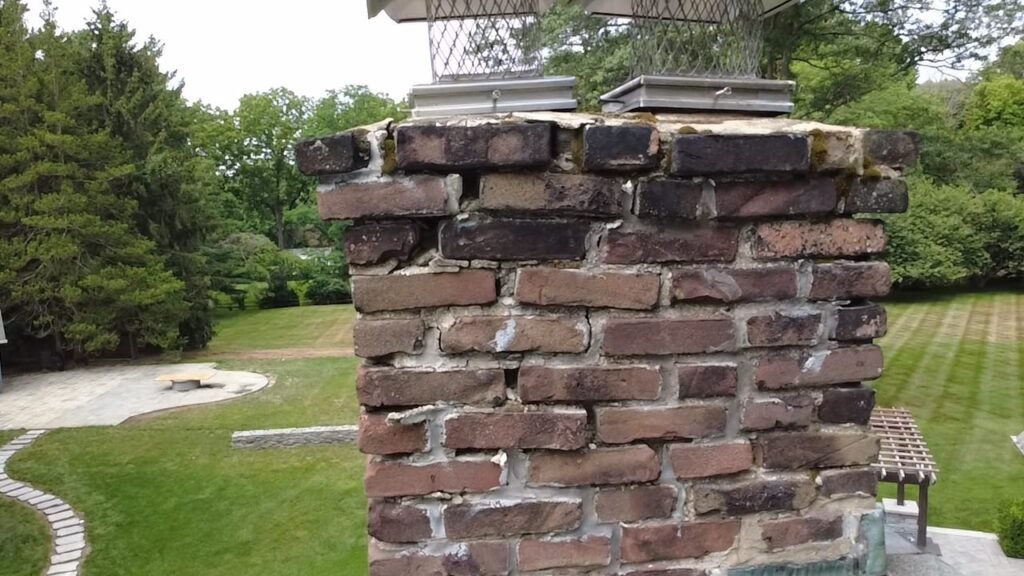 Brick chimney with worn mortar below the crown