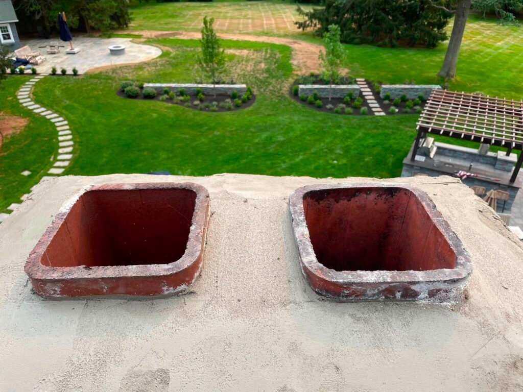 Two open clay flue tiles on a sand-colored crown
