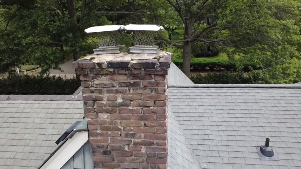 Brick chimney with two metal caps, seen from across the roof