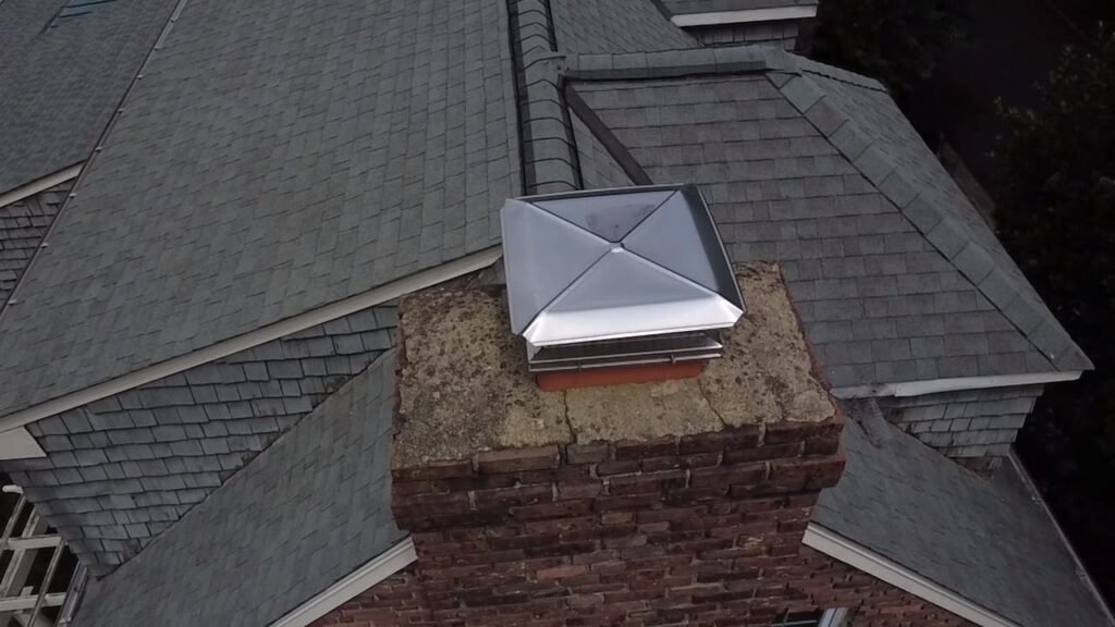 Chimney with a metal cap, seen from above the roof