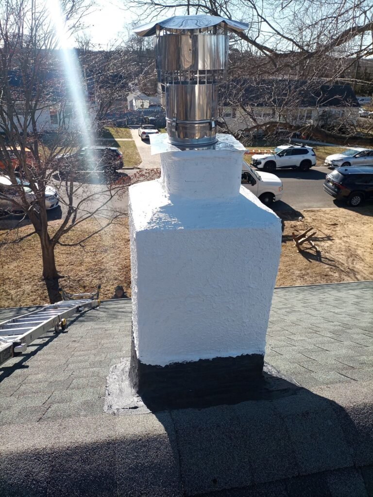 Chimney with a freshly applied white stucco coating and a stainless steel flue pipe, seen from the roof