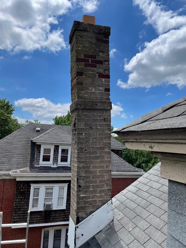 Tall original brick chimney with weathered brick above the roofline