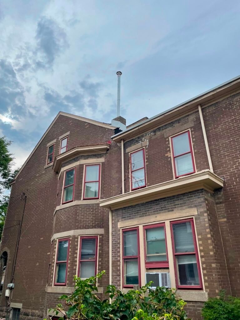 Brick house with a slim metal flue pipe at the top of the chimney